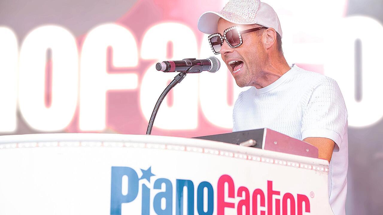 Piano entertainer singing and playing keyboard on an outdoor stage during a live event
