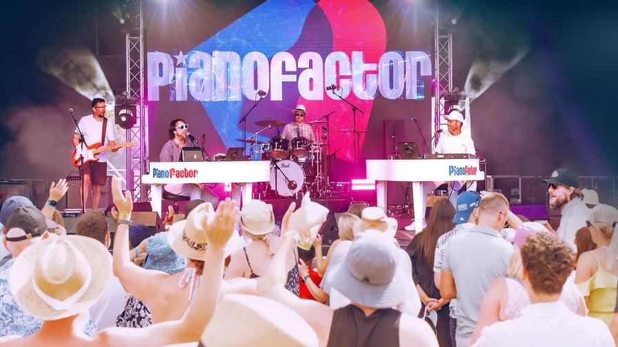 Duelling pianos live performance with audience singing and hands raised at a PianoFactor event